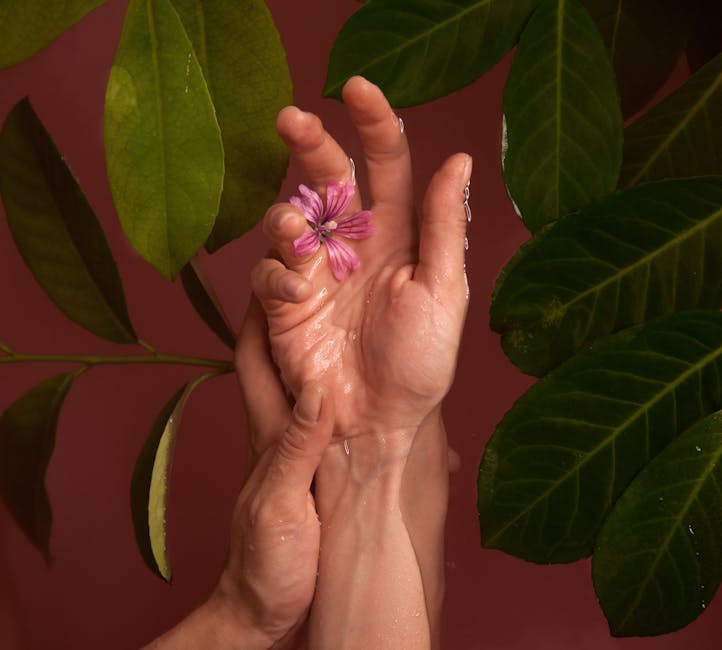 Aesthetic photograph of hands intertwined with a pink flower and green leaves, showcasing natural beauty.
