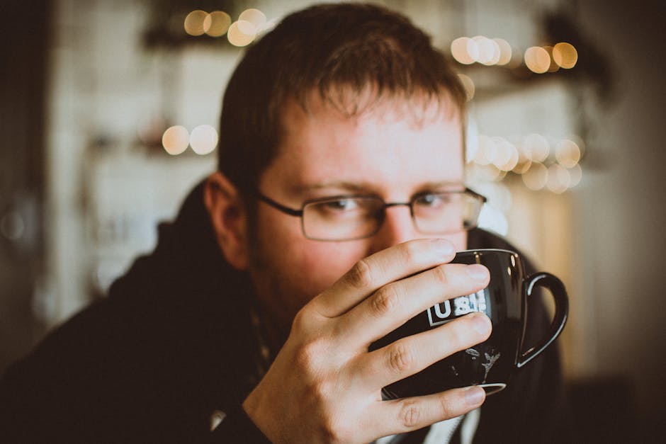 A man with glasses enjoys a warm coffee indoors, creating a relaxed atmosphere.