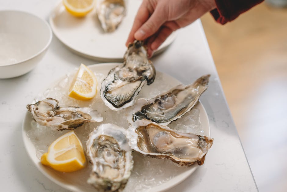 A close-up of fresh oysters on ice with lemon slices, perfect for seafood lovers.