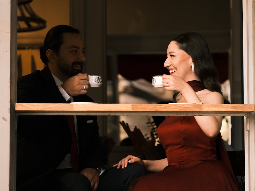 A couple dressed elegantly enjoying coffee inside a cozy cafe setting.