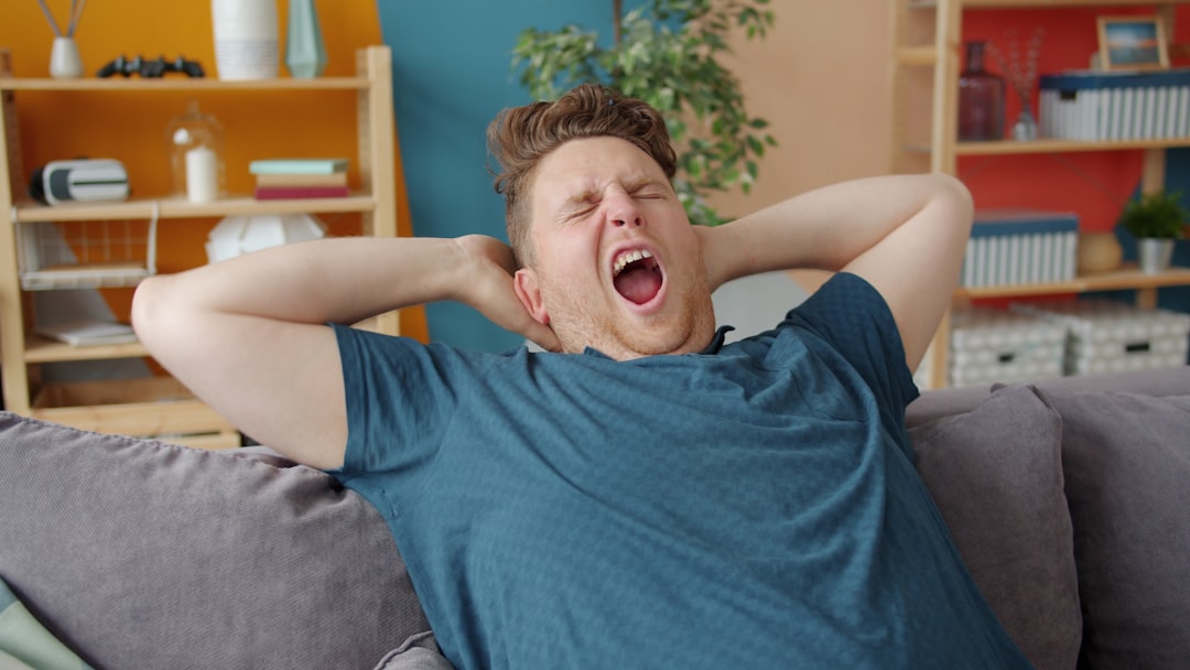 Man yawning widely with hands behind his head.
