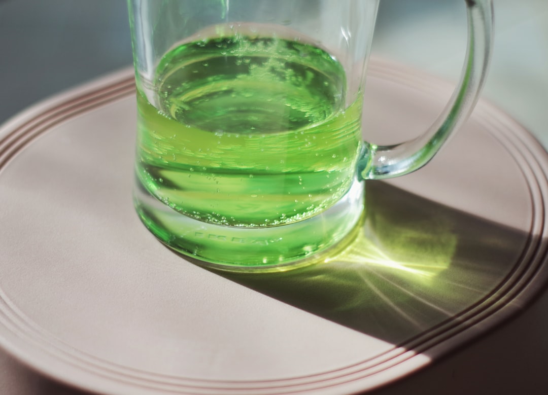 a glass of green liquid sitting on top of a white plate