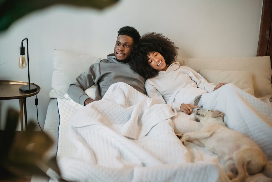 A couple enjoys a relaxing moment with their dog in a cozy bedroom setting.