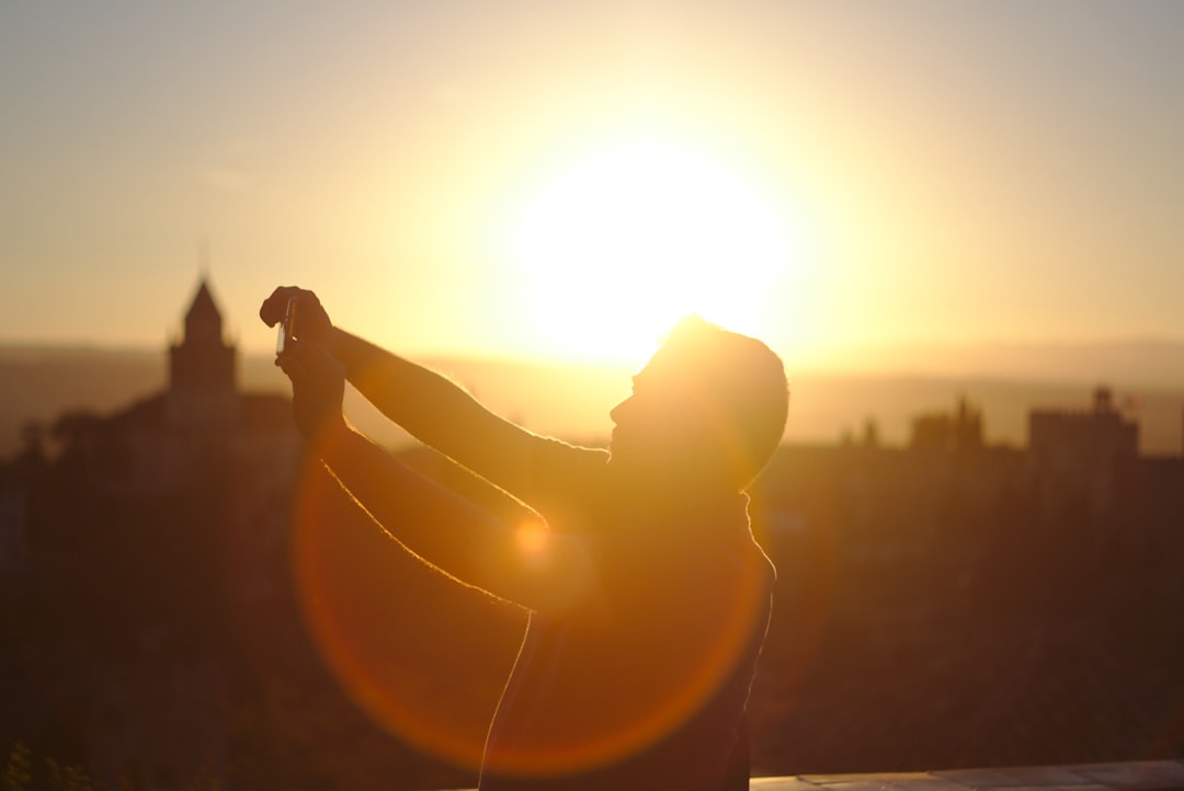 man raising hands under sunset