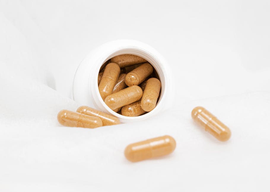 Brown capsules spilling from a white bottle on a bright white background, ideal for health and wellness themes.